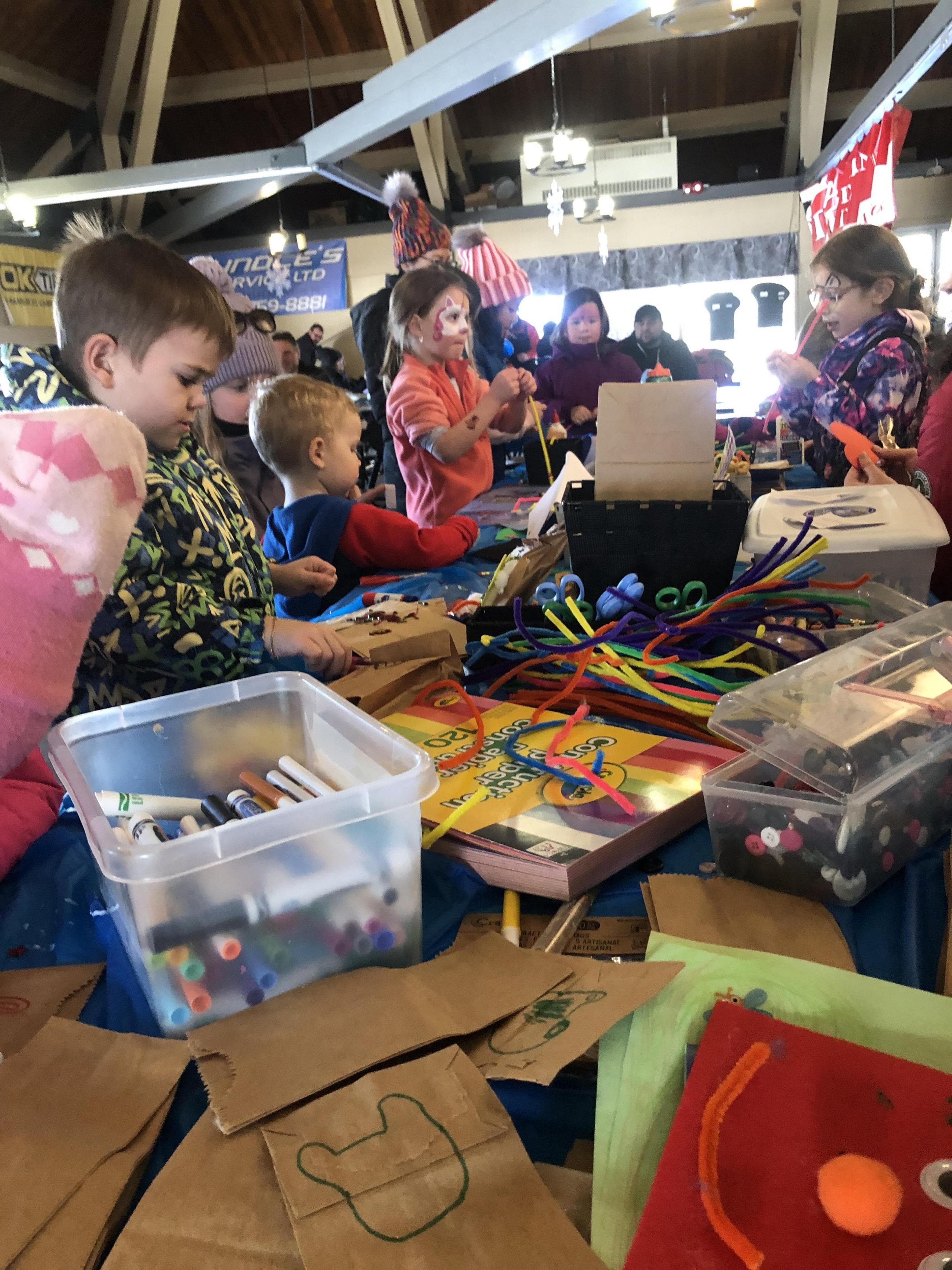 Children crafting their own projects at Sno-Fest Village, surrounded by colorful materials and supplies